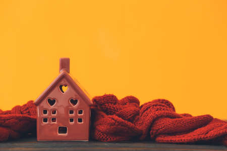Figure of house and warm scarf on table. Concept of heating seasonの写真素材