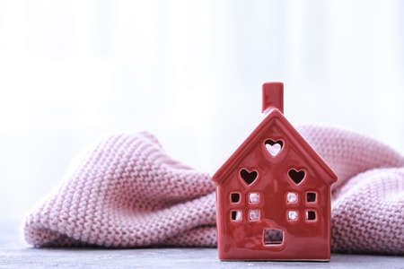 Figure of house and warm scarf on table. Concept of heating seasonの写真素材