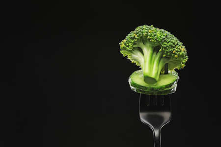 Fork with broccoli and cucumber on dark backgroundの写真素材