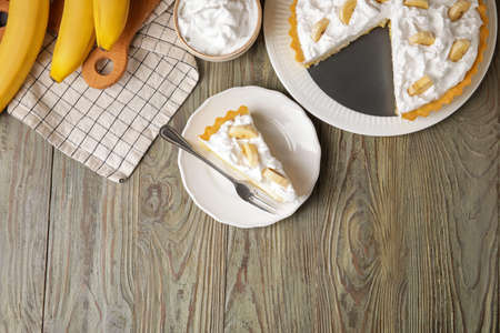 Plate with piece of tasty banana pie on wooden backgroundの写真素材