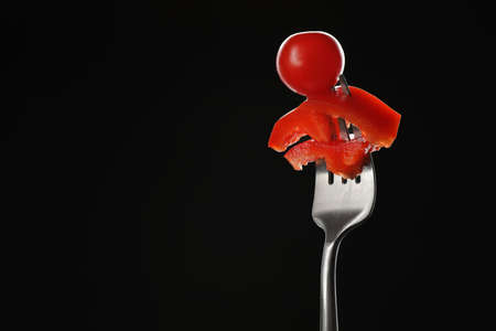 Fork with tomato and pepper on dark backgroundの写真素材