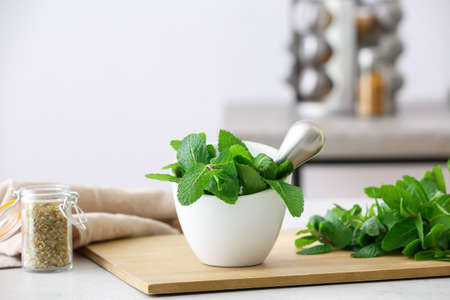 Mortar with mint and pestle on light table in kitchenの写真素材