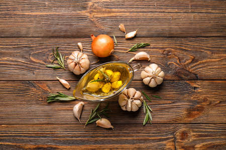 Gravy boat with garlic oil, rosemary and onion on wooden backgroundの写真素材