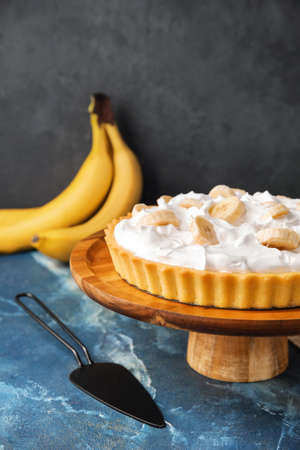 Dessert stand with tasty banana pie on color tableの写真素材