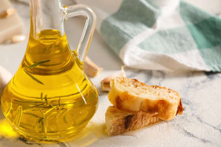 Jug of oil, bread and garlic on light backgroundの写真素材