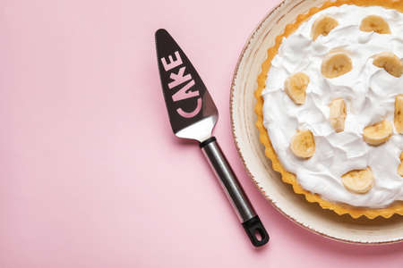Plate with tasty banana pie and spatula on color backgroundの写真素材