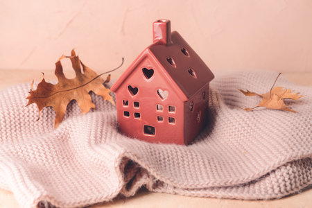 Figure of house, autumn leaves and warm scarf on table. Concept of heating seasonの写真素材