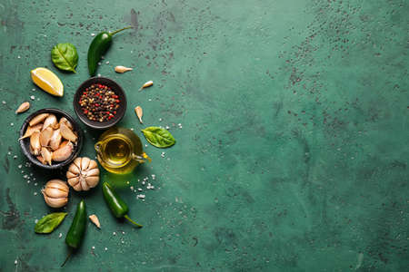 Jug of oil, bowls with spices and garlic on color backgroundの写真素材
