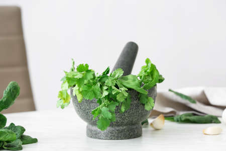 Mortar with herbs and pestle on light tableの写真素材