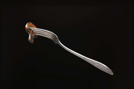 Fork with piece of mushroom on dark backgroundの写真素材