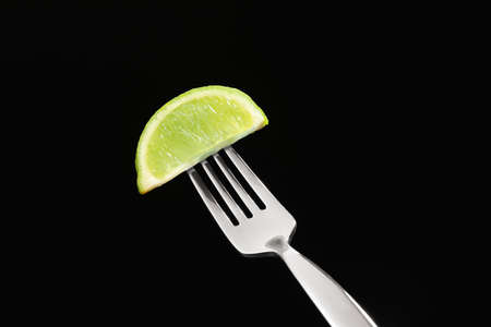Fork with piece of lime on dark backgroundの写真素材