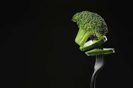 Fork with broccoli and cucumber on dark backgroundの写真素材