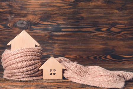 Figures of house and warm scarf on table. Concept of heating seasonの写真素材
