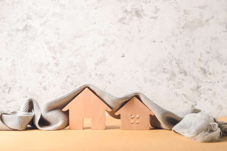 Figures of house and warm scarf on table. Concept of heating seasonの写真素材