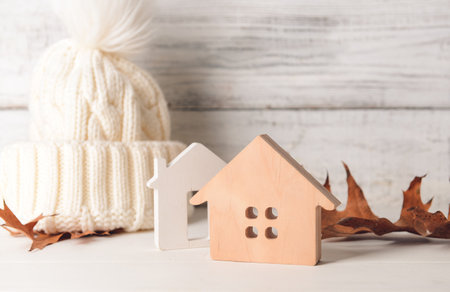 Figures of house, autumn leaves and warm hat on table. Concept of heating seasonの写真素材