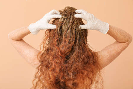 Young woman using henna hair dye on color backgroundの写真素材