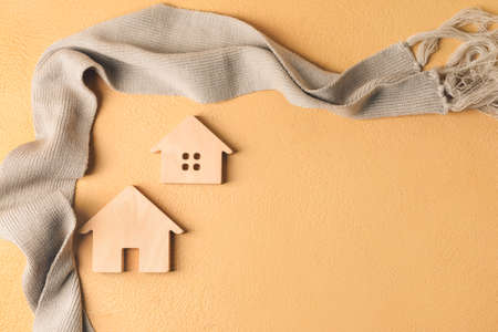 Figures of house and warm scarf on table. Concept of heating seasonの写真素材