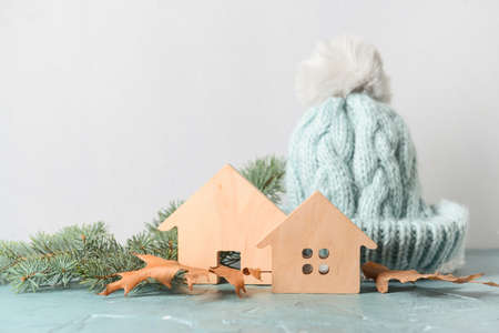 Figures of house, autumn leaves, fir branches and warm hat on table. Concept of heating season
