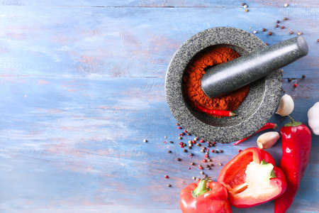 Mortar with chili pepper powder and pestle on color wooden backgroundの写真素材