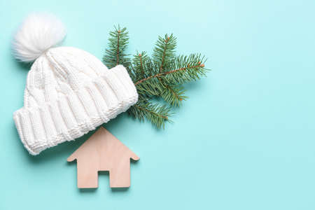 Figure of house and warm hat on color background. Concept of heating seasonの写真素材