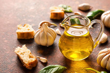 Jug of oil, bread and garlic on grunge backgroundの写真素材