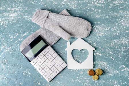 Figure of house, calculator, money and warm mittens on table. Concept of heating seasonの写真素材