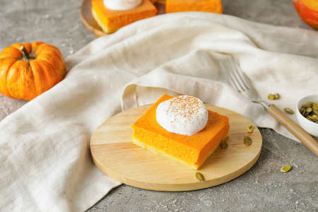 Board with piece of tasty pumpkin pie on grunge backgroundの写真素材