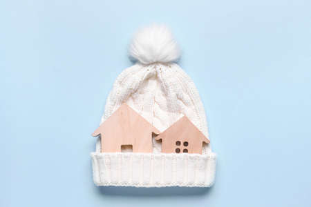 Figures of house and warm hat on color background. Concept of heating seasonの写真素材