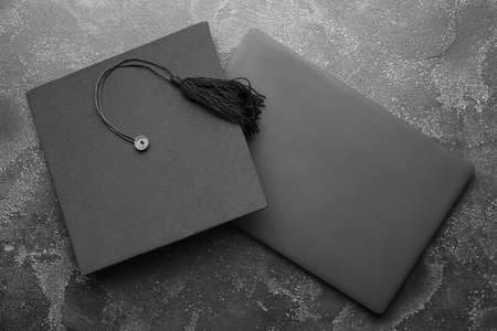 Graduation hat with laptop on dark backgroundの写真素材