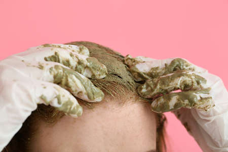 Young woman using henna hair dye on color background, closeupの写真素材