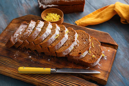Board with tasty gingerbread cake on color wooden background