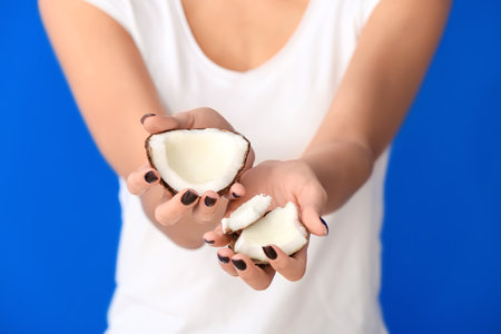 Young woman with coconut on color background, closeupの写真素材