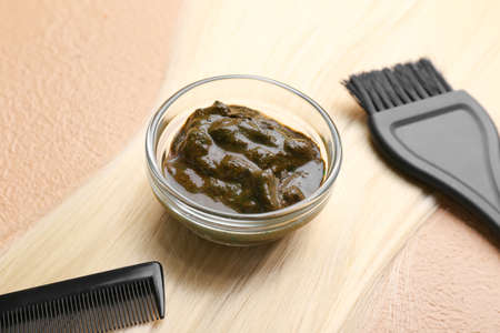 Bowls with henna, hair, comb and brush on color background, closeupの写真素材