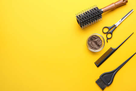 Bowl with henna and hairdresser's supplies on color backgroundの写真素材