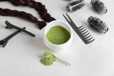 Bowl with henna, braided strand and hairdresser's supplies on light backgroundの写真素材