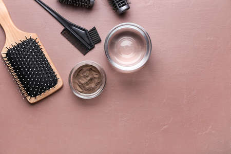 Bowl with henna, hairdresser's supplies and glass of water on color backgroundの写真素材