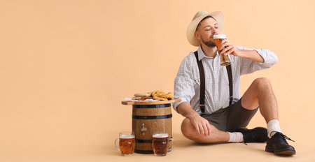Young man in traditional German clothes drinking beer on beige background with space for textの写真素材