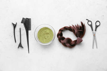 Bowls with henna, braided strand and hairdresser's supplies on white backgroundの写真素材