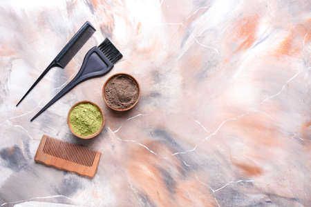 Bowls with henna, hair combs and brush on color backgroundの写真素材