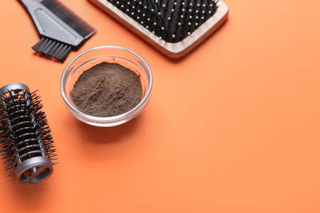 Bowl with henna and hairdresser's supplies on color backgroundの写真素材