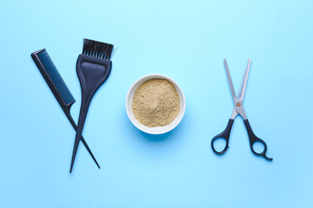 Bowl with henna and hairdresser's supplies on color backgroundの写真素材