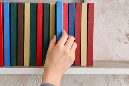 Woman taking book from shelf, closeupの写真素材