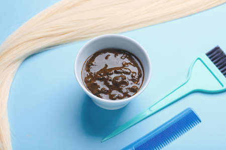 Bowl with henna, hair and hairdresser's supplies on color background, closeupの写真素材