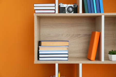 Shelf unit with books and decor on color backgroundの写真素材