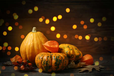 Autumn composition with pumpkins on dark wooden background with blurred lightsの写真素材