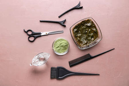 Bowls with henna and hairdresser's supplies on color backgroundの写真素材