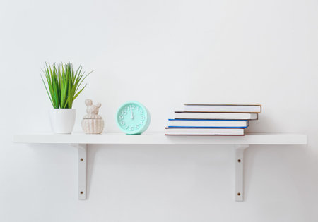 Shelf with books and decor on light backgroundの写真素材
