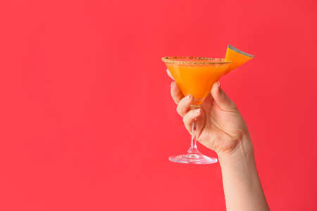 Female hand with glass of tasty pumpkin pie martini on color backgroundの写真素材