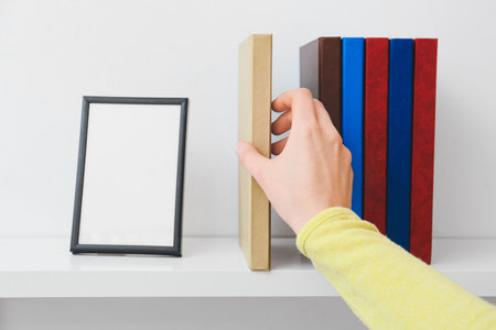 Woman taking book from shelf, closeupの写真素材