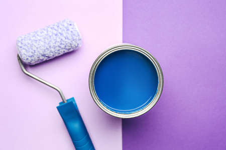 Can of blue paint and roller on color backgroundの写真素材